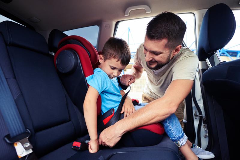 اب يقوم بمساعدة ابنه على الجلوس في مقعد السيارة 