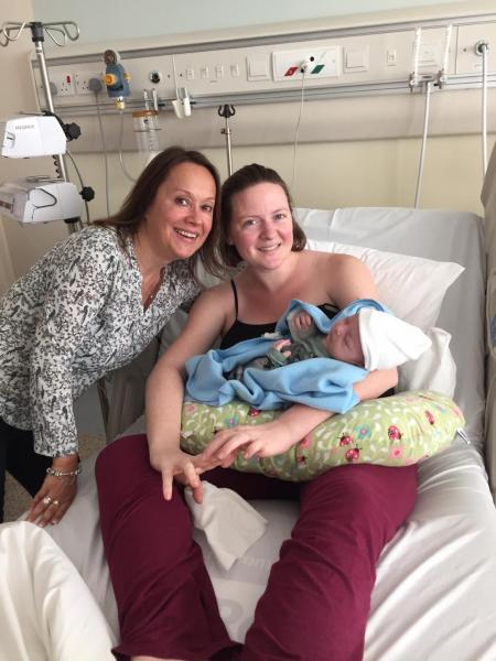صورة لأم وطفلها على سرير المشفى بعد الولادة برفقة الدولا المساعدة لها 