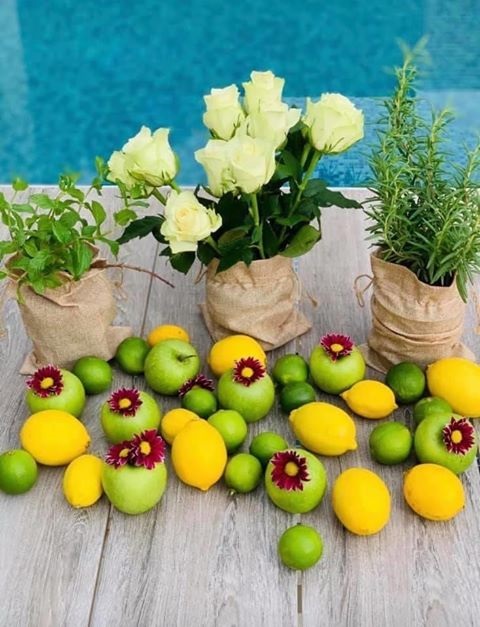 حبات من الليمون والتفاح مستخدمة لتزيين طاولة السفرة مع الورود