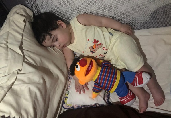 طفل نائم في سريره مع لعبته