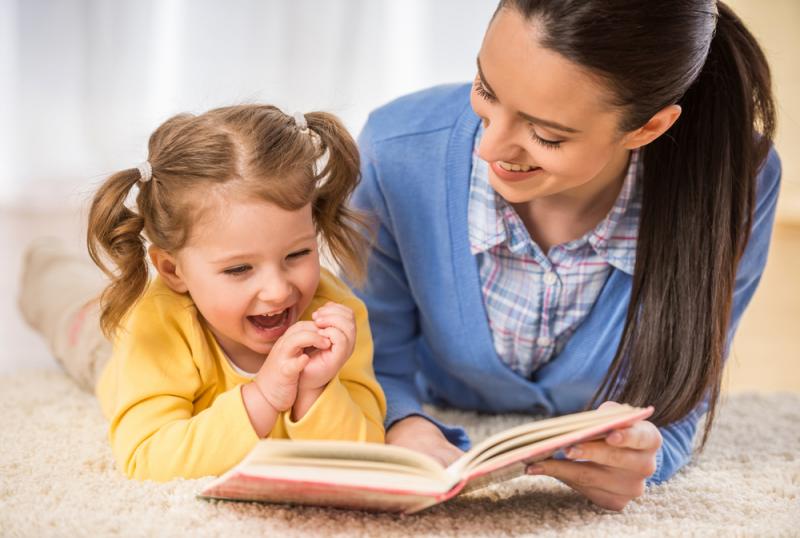 أم تقرأ كتاب مع طفلتها الصغيرة.