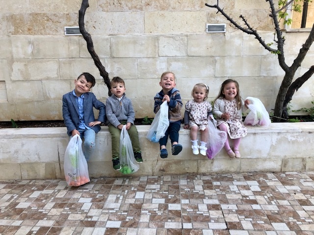 خمس أطفال يجلسون على سور حديقة 