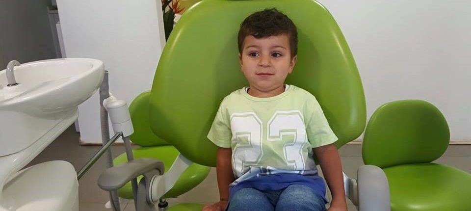 طفل يجلس على كرسي المعاينة في عيادة دكتور الأسنان 