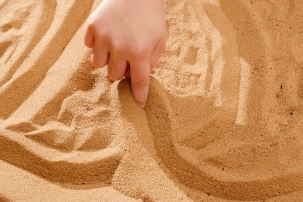 طفل يرسم على الرمل