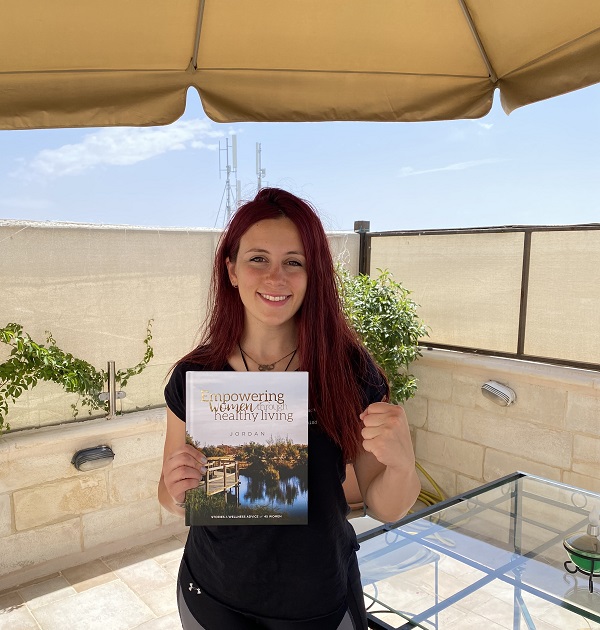 woman smiling and holding the Empowering Women through Healthy Living book