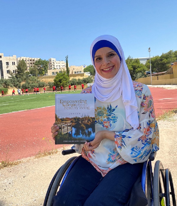 woman smiling and holding the Empowering Women through Healthy Living book