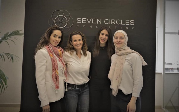 4 women standing in front of a wall that has seven circle's logo in it