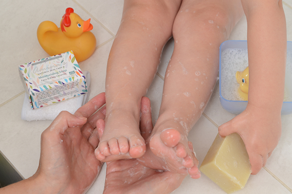 A mom using Amina's Soup to clean her kid in the bath 