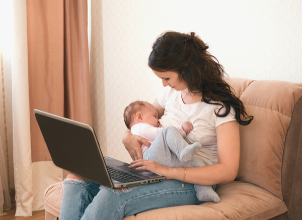 A Mom breastfeeding her kid while working on her laptop