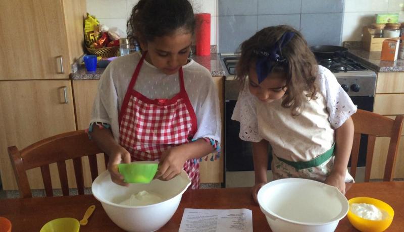 girls wearing an apron and cooking something sweet 