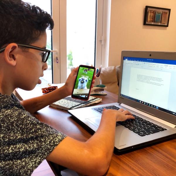 a kid playing with his mobile and laptop