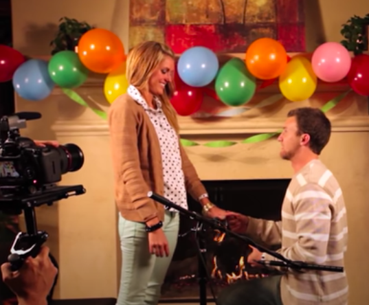 a guy proposing to a girl in a place full of baloons