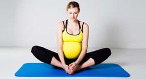 A pregnant mom making the Butterfly Pose or Tailor Stretching: