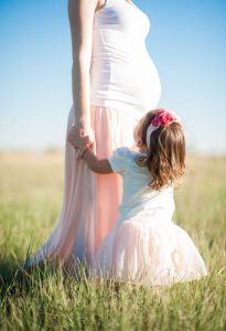 a picture of a pregnant mom and her first kid in a garden 