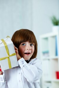 a kid holding a gift wrapped in ribbons 