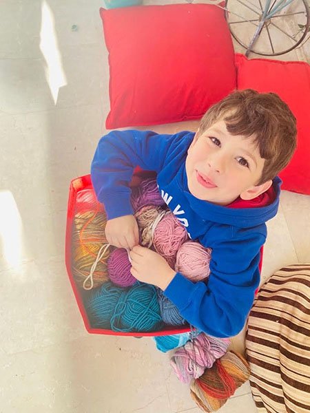 a little boy holding a box full of yarn