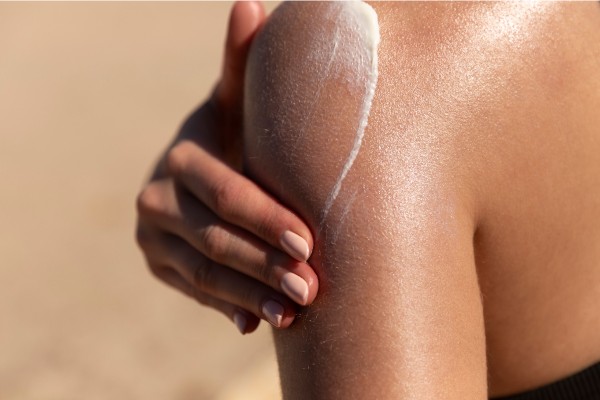 A girl spreading a sunscreen on her back 